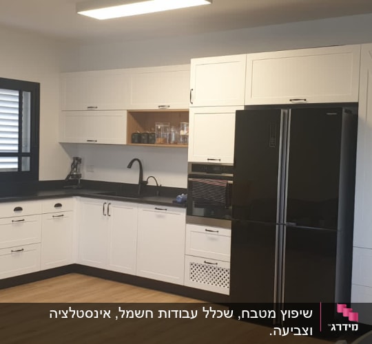 מטבח חדש עם ארונות לבנים ומקרר שחור